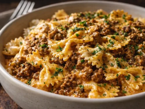A White Bowl Filled With Creamy Cajun Beef Alfredo Bowties Topped With