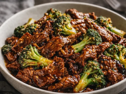 A Plate Of Chinese Beef Broccoli Served Over White Rice With A